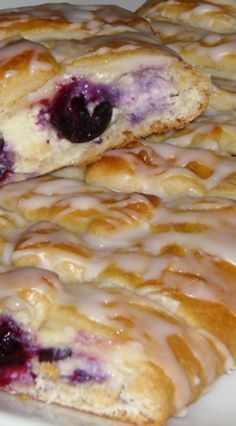 two blueberry scones sitting on top of a white plate covered in icing