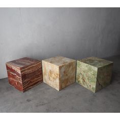 three different colored marble blocks sitting next to each other on the cement floor in front of a gray wall