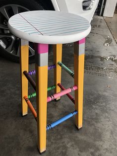 a white car parked next to a colorful stool