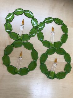 three green plates with candles in them on a table