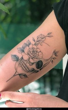 a woman's arm with a skull and flowers on it