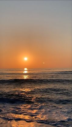 the sun is setting over the ocean with waves