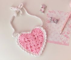 a crocheted pink and white heart shaped object next to a pair of scissors