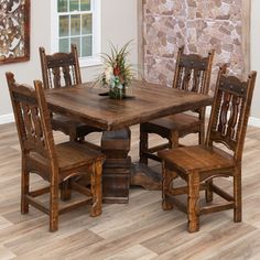 a dining room table and chairs in front of a stone wall with a potted plant on it