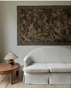 a white couch sitting in front of a large tapestry