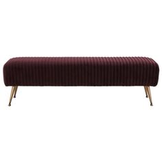 an upholstered bench with gold legs and a maroon velvet cover on it, against a white background