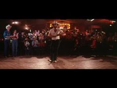 a man standing on top of a wooden floor in front of a group of people