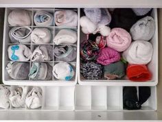 two bins filled with different types of baby blankets and mittens in them, sitting on top of a counter