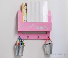 a pink shelf with two buckets holding pens, pencils and paper on it