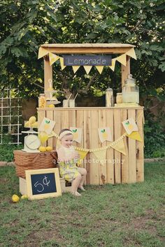 a baby sitting in front of a lemonade stand