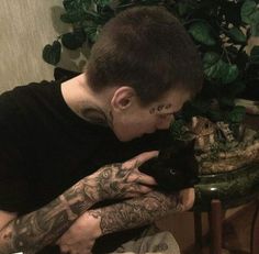 a man with tattoos holding a black cat