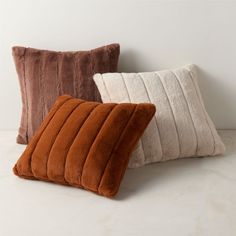 three different colored pillows on a white surface