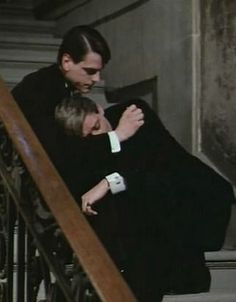 a man and woman hugging on the stairs in black and white, holding each other