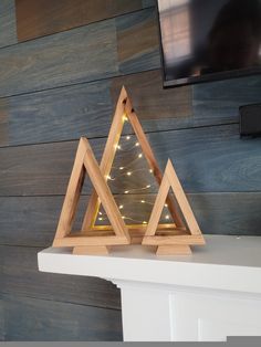 a wooden triangle with lights on it sitting on top of a white mantle in front of a tv