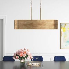 a dining room table with blue chairs and flowers in the vase on the end, hanging from an overhead light fixture