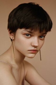 a woman with short hair and piercings on her ears is looking at the camera