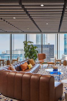 a living room filled with lots of furniture and large windows overlooking the cityscape