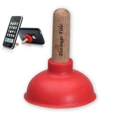 an iphone holder with a wooden stick sticking out of it's side and a cell phone in the background