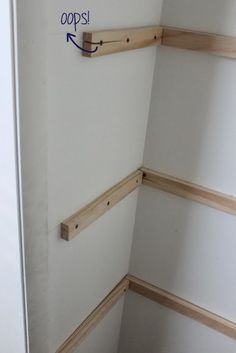 the corner of a room with some shelves on one side and an arrow in the other