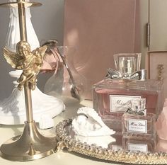 an assortment of perfumes on a table next to a candle and figurine