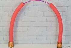 two pink and gold colored arch stands against a white brick wall