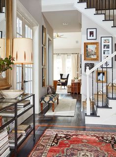 an entry way with stairs, rugs and pictures on the wall in front of it