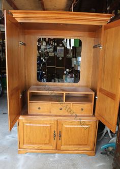 a wooden cabinet with a mirror on top and drawers in the bottom half, sitting next to other furniture