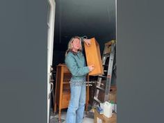 a woman standing in a room holding a piece of paper and looking at the camera