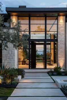 a modern house with large glass doors and stone steps leading up to the front door