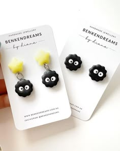 two black and yellow earrings with eyes on them sitting next to each other in front of a white card