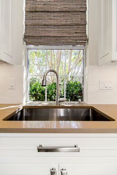 a kitchen sink under a window next to cabinets