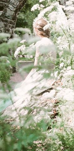 a woman sitting on top of a rock next to flowers