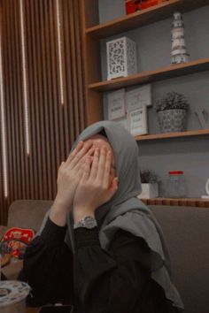 a woman covering her face while sitting at a table