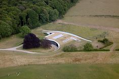 an aerial view of a building in the middle of a field with trees around it