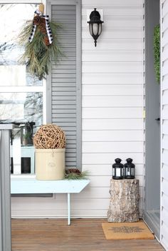 the front porch is decorated for christmas with wreaths and lantern holders on it's side