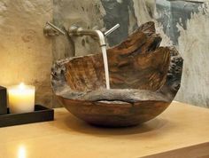 a wooden bowl shaped sink sitting on top of a counter next to a lit candle