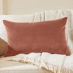 an orange pillow sitting on top of a couch next to a white blanket and pillows