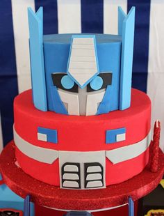 a red and blue cake with a transformer face on it's bottom tier