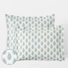 two pillows with blue and green designs on them, one has a white pillow case