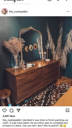 a dresser with a mirror and some plants on it in a room that has green walls