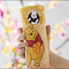 a person holding up a cup with a straw in it and winnie the pooh sticker on it