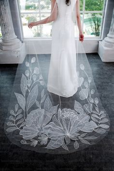 a woman standing in front of a window with a veil over her head and flowers on the floor