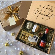 an open gift box with wine, chocolates and other holiday treats on a table