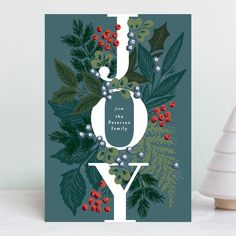 a christmas card with the word joy on it, surrounded by holly leaves and berries