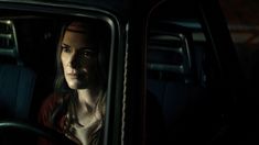 a woman sitting in the passenger seat of a car at night with her eyes closed