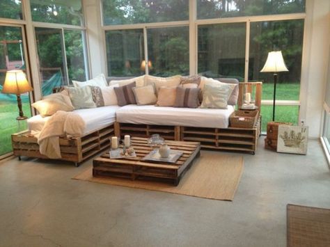 spacious-bright-living-room-with-large-windows-containing-a-pallet-couch-decorated-with-white-cream-and-beige-cushions-with-a-pallet-coffee-table-nearby Pallet Couch Cushions, Palette Sofa, Pallet Furniture Couch, Pallet Furniture Cushions, Table Palette, Pallet Home Decor, Diy Pallet Couch, Diy Pallet Sofa, Pallet Furniture Designs