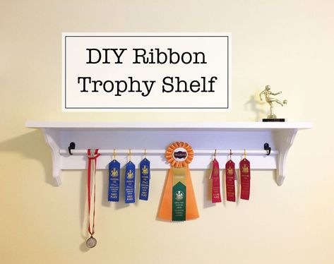 I did this project about two months ago when I was looking for a nice way to display our oldest’s growing collection of award ribbons and medals but couldn’t find a display setup that I liked or was remotely affordable. The whole project was super easy and done start-to-finish within two days. | This post contains affiliate links | Materials      lumber (I used a 1x8" board for the shelf top and 1x6" board for the back)  two decorative shelf brackets (or two pieces of wood cut at 45 de… Trophy Display Ideas, Trophy Display Shelves, Baseball Shelf, Diy Trophy, Bed Riser, Trophy Wall, Woodshop Projects, Trophy Shelf, England Lifestyle