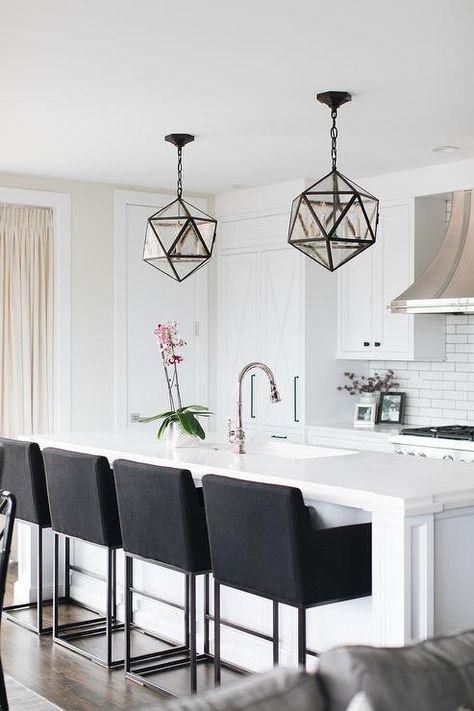 Contemporary white kitchen with black accents is illuminated by two seeded glass polyhedron pendants hung above a white island fitted with a sink and a polished nickel gooseneck faucet fixed to a white quartz countertop seating four black upholstered barstools. Black Bar Stools Kitchen, White Kitchen Bar Stools, Dining Room Island, Bar Stools For Kitchen Island, Bar Stools For Kitchen, Stools For Kitchen, Marble Herringbone, Mosaic Marble, Bar Stools Kitchen Island