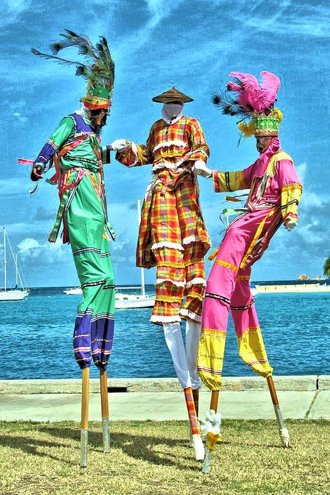 Moko jumbies at dockside, St. Croix, U.S. Virgin Islands. The eye-catching art of stilt dancing came to the Caribbean with enslaved West Africans, who brought their indigenous religions, folklore and festivities from home.  In African villages, the 'moko' was the spiritual guardian and healer, towering high enough to reach any evil spirits and drive them away.  Jumbies groove to the rhythm of African drums with lively choreography that combines dancing and acrobatics.  © JAOS, 2014 Moko Jumbie Art, Caribbean Culture West Indies, African Celebrations, Caribbean Art West Indies, African Carnival, African Theatre, Caribbean Folklore, Moko Jumbie, Carnival Caribbean