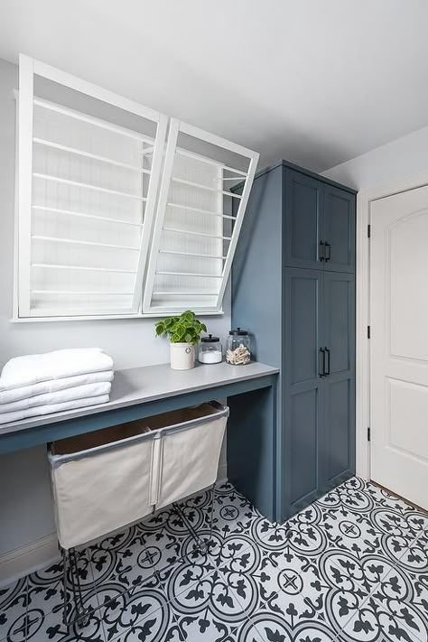 White drying racks are mounted over a white quartz countertop fitted above vintage laundry carts placed on black and white cement tiles beside blue shaker cabinets donning matte black hardware. Transitional Bathroom Design, Laundy Room, Wall Mounted Drying Rack, Dream Laundry Room, Mudroom Laundry Room, Laundry Room Layouts, Laundry Room Renovation, Laundry Design, Modern Laundry Rooms